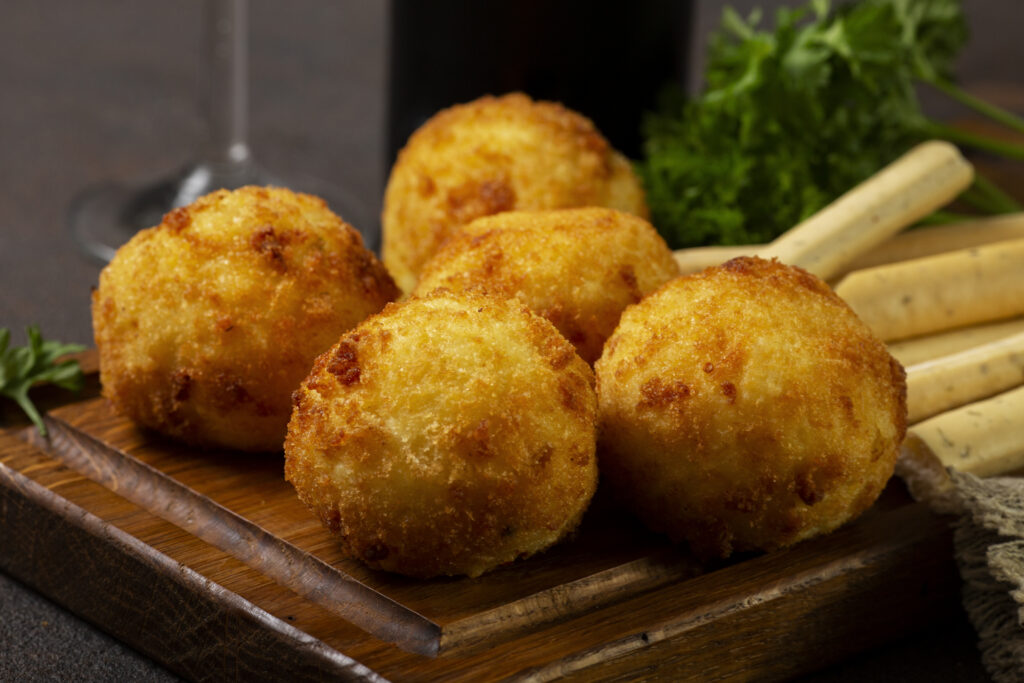 Arancini sicilianos servidos em tábua de madeira