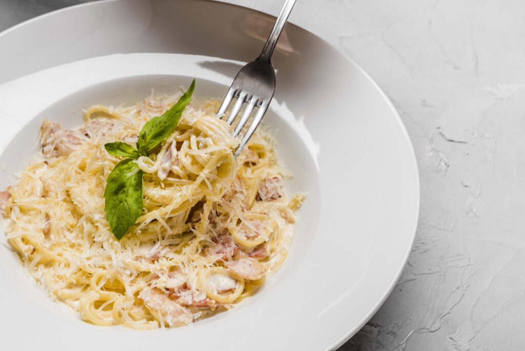 Prato de Spaghetti alla Carbonara com queijo ralado e manjericão