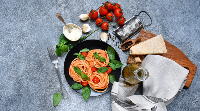 Prato de massa italiana com molho de tomate, manjericão e ingredientes frescos.