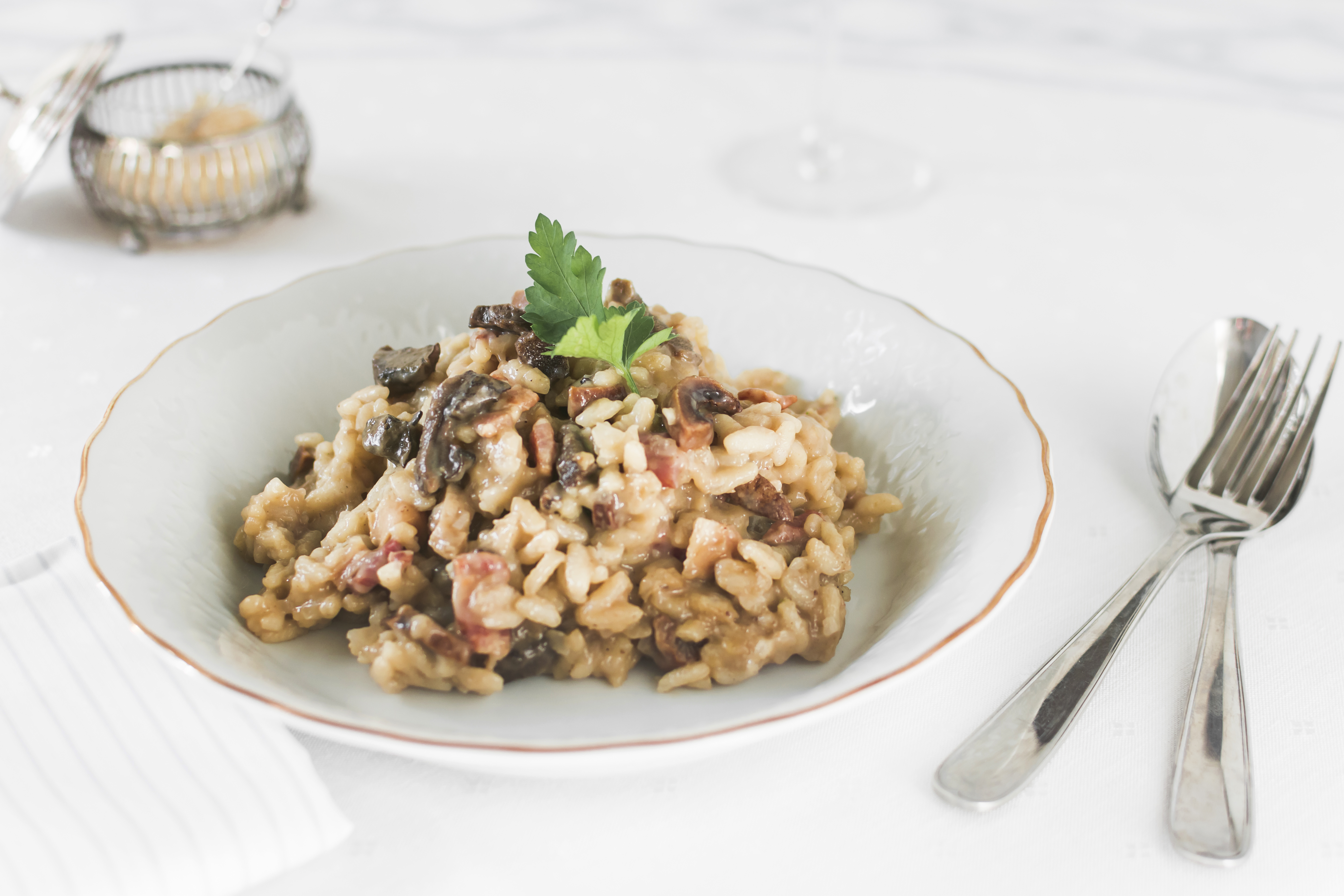 Risoto de funghi servido em prato branco com ervas frescas