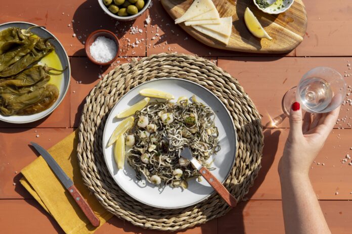 Prato tradicional da Ligúria com frutos do mar, pimentões grelhados, azeitonas e queijo servido em um ambiente mediterrâneo.