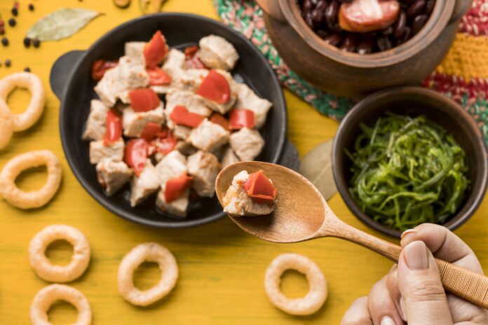 Prato rústico da culinária umbriana servido com cubos de carne, tomate e acompanhamentos tradicionais em uma mesa decorada com elementos regionais.